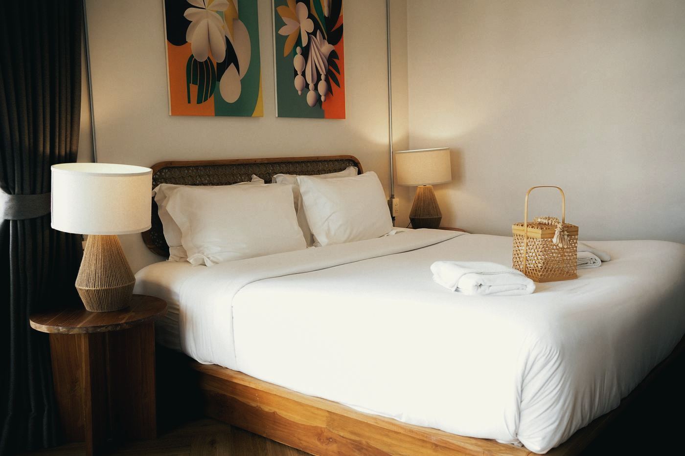 Bed dressed in white linen with a woven welcome basket