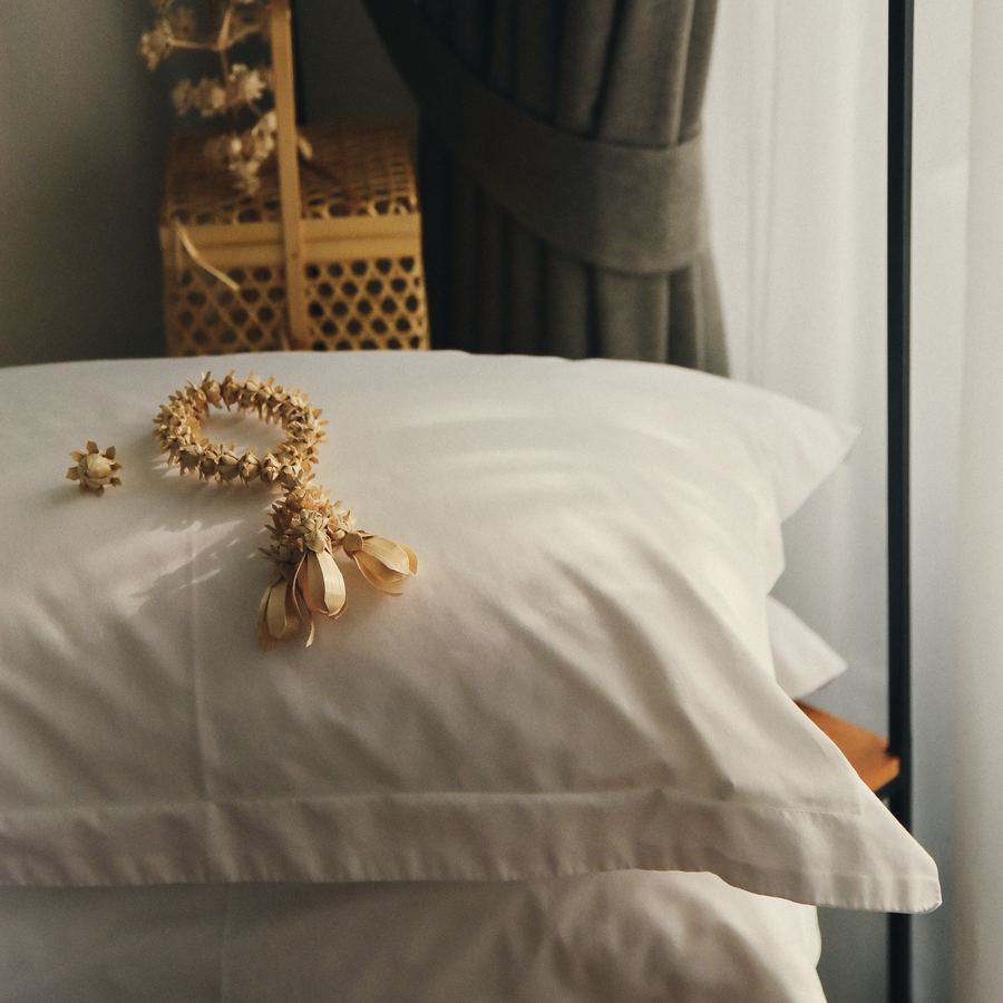 Soft pillow on white linen with a woven garland